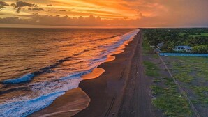 A beach with a long stretch of sand and a few buildings in the distance. - Hotel nuevo amanecer (Chiquimulilla)