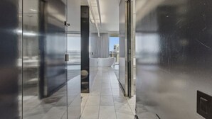 A modern hotel corridor with a glass wall, a bathtub, and a view of the city.