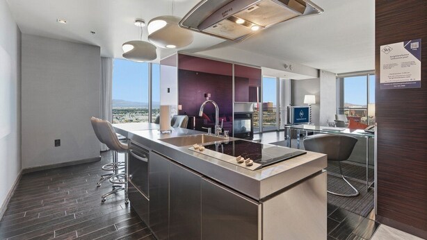 A modern kitchen with a large island, bar stools, and a view of the city.