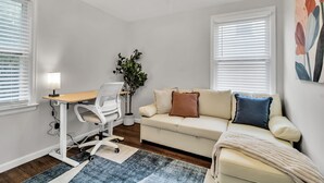 A room with a desk, chair, sofa, and a plant. - Modern Home 3 Minutes from Airport! (Cheektowaga)