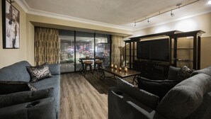 Un salon moderne comprenant un canapé, un téléviseur et un coin repas avec une table et des chaises.