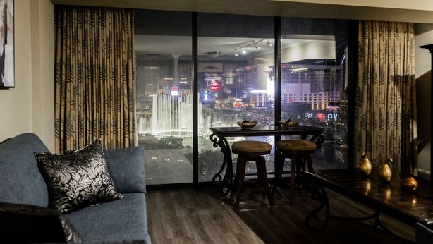 Un salon doté d’une grande fenêtre donnant sur une vue panoramique de la ville la nuit.