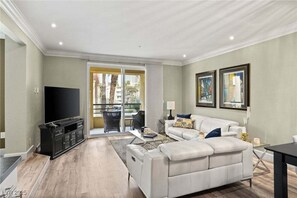 Un salon moderne doté d’un téléviseur à écran plat, d’un canapé blanc, d’une table basse et d’un coin repas avec une table et des chaises.