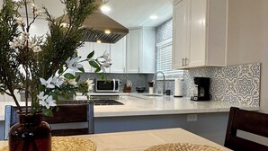 A modern kitchen with white cabinets, a microwave, and a coffee maker on the counter. - Gorgeous 3-bedroom 4 bed home in San Diego (San Diego)