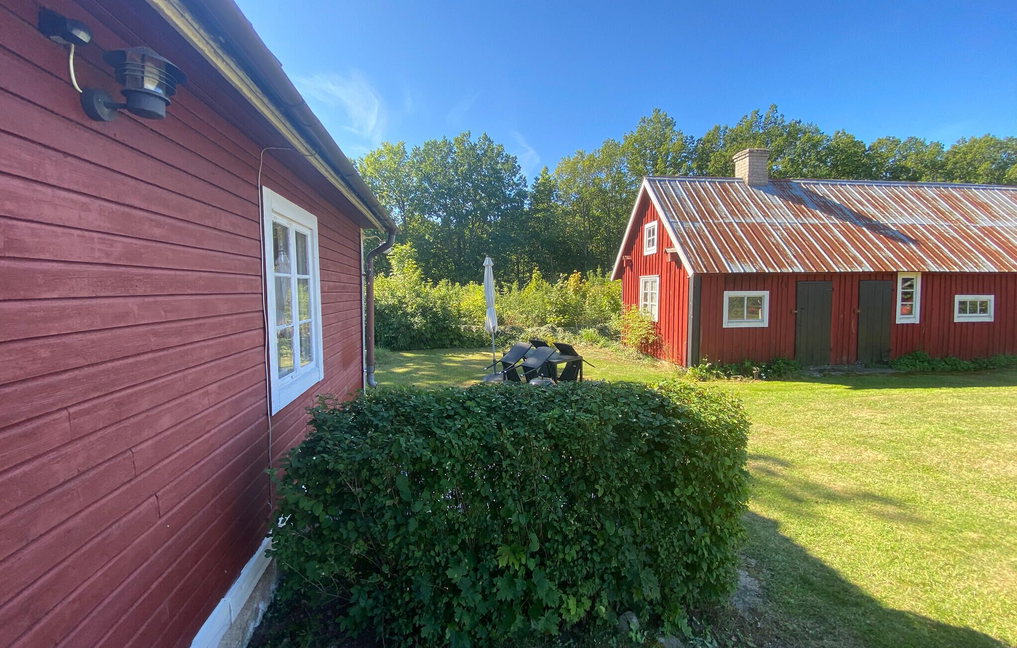 Une maison en bois rouge, avec une fenêtre blanche et un toit en métal.