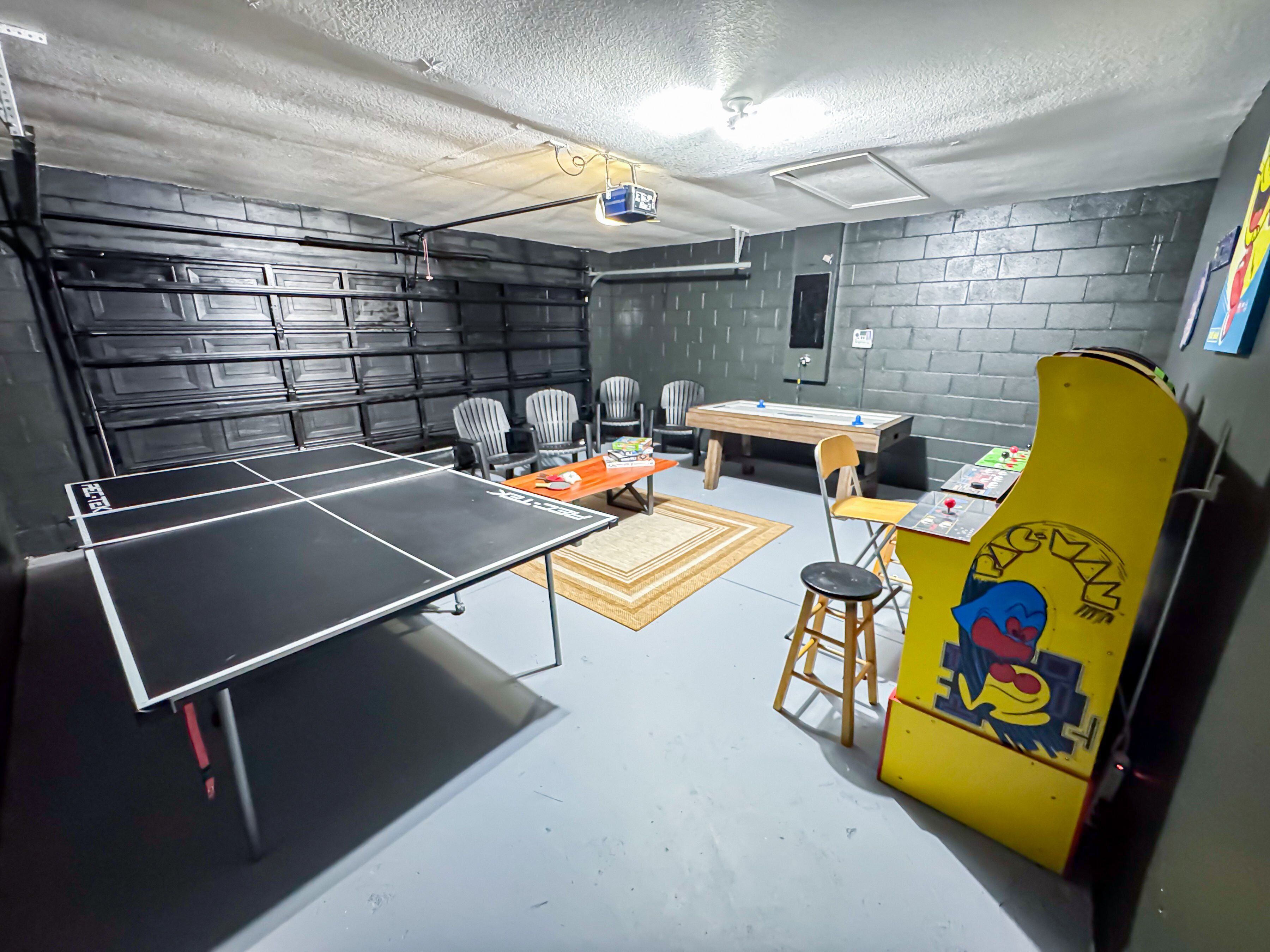 Een kamer met een tafeltennistafel, stoelen, een tafelvoetbaltafel en een tafelvoetbaltafel met een cartoonfiguur.