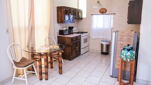 Een kleine keuken met een eettafel, stoelen en een kleine koelkast.