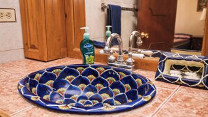 Een badkamer met een blauwe keramieken wastafel, een houten deur en een spiegel die een blauwe handdoek weerkaatst.