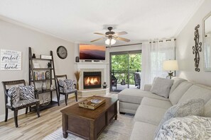 Una sala de estar con chimenea, un sofá, una mesa de centro, una estantería y un televisor.