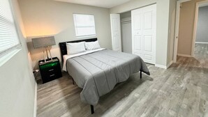 Une chambre à coucher avec un lit, des tables de chevet, une lampe, une armoire et une porte.