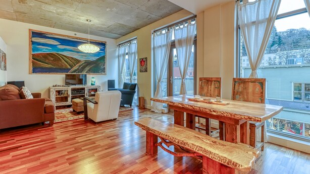Un salon spacieux avec une table à manger en bois, un canapé et un grand tableau accroché au mur.