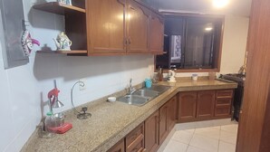 Una cocina con encimeras de granito, armarios de madera, un lavamanos y una ventana.