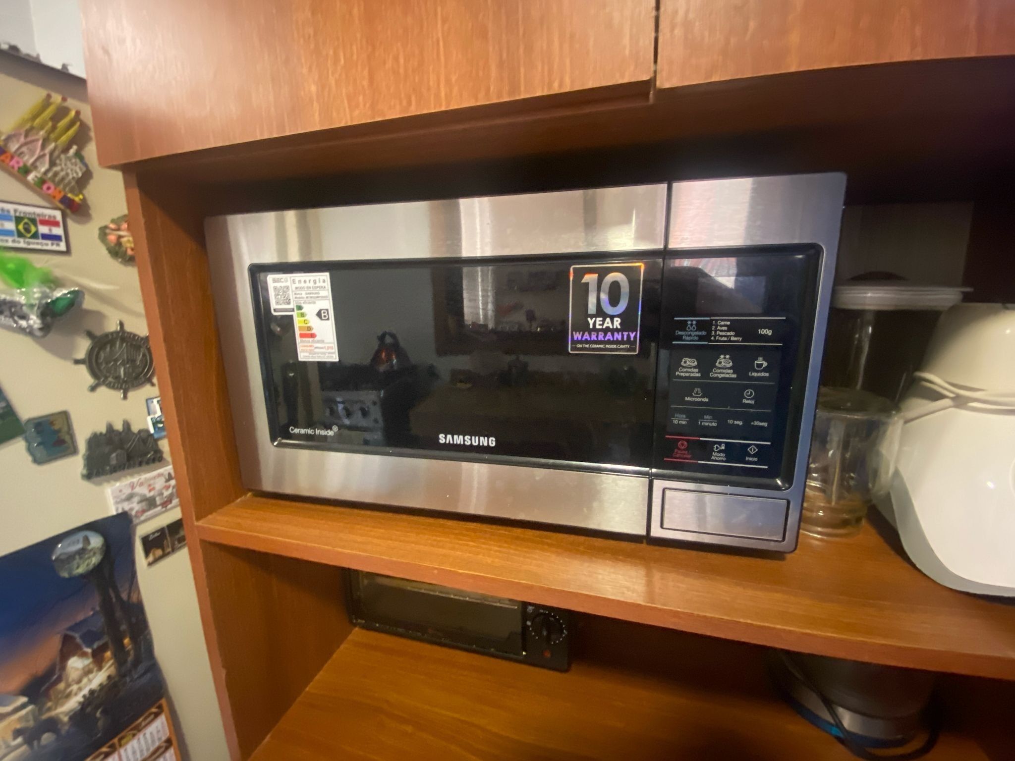 Un microondas Samsung sobre una repisa de madera con un adhesivo que indica 10 años de garantía.