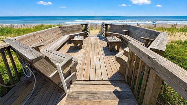A wooden deck with benches and tables, leading to a beach with the ocean in the background. - A Sense of Porpoise - 4 BR Oceafront Townhome in Southern Shores (Southern Shores)