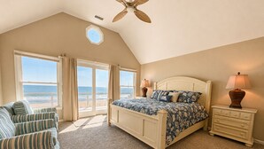 A bedroom with a bed, a chair, a nightstand, and a ceiling fan. - A Sense of Porpoise - 4 BR Oceafront Townhome in Southern Shores (Southern Shores)
