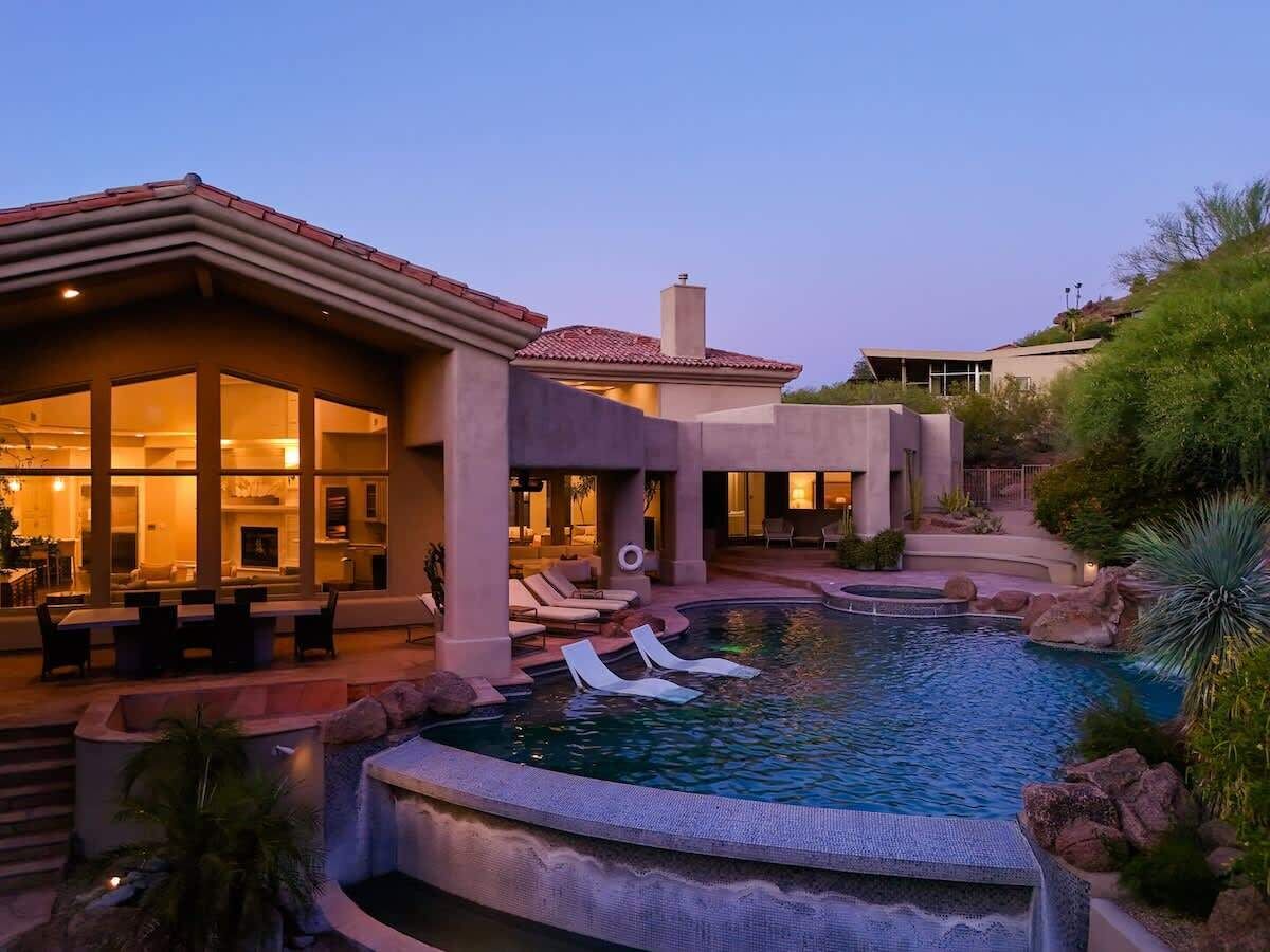 A modern resort with a swimming pool, outdoor seating, and a well-lit building.