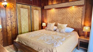 Ein Zimmer mit Holzboden, einem Bett, zwei Nachttischen und einem gewobenen Kopfteil.