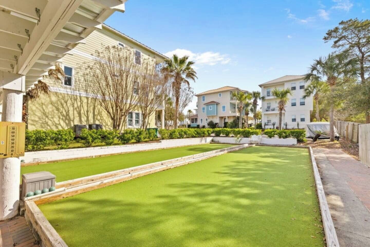 A courtyard with a green lawn, a pool, and buildings with balconies.