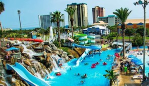 Ein Wasserpark mit mehreren Rutschen und Pools, umgeben von Palmen und Gebäuden.