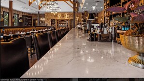 Una barra de mármol largo y pulido, con cabinas de cuero y un techo alto con vigas a la vista y candelabros.