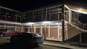 A multi-story building with a covered outdoor area, a staircase, and a parked car.