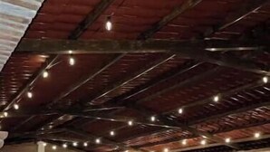 An indoor space with a high ceiling, exposed beams, and string lights.