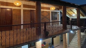 A building with a covered porch, brick walls, and a staircase leading to an upper level.