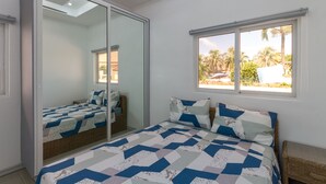 Une chambre à coucher avec un lit, une armoire, une fenêtre donnant sur un beau paysage et un luminaire au plafond.