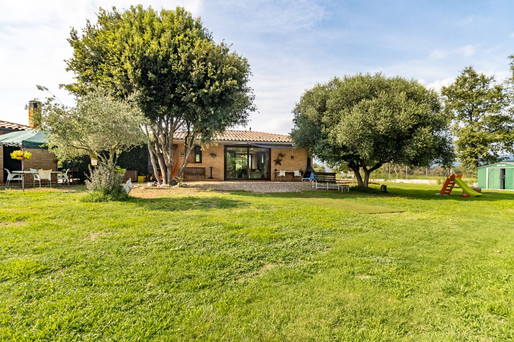 A house with a tiled roof, a covered patio, and a grassy yard.