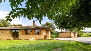 Una casa de dos pisos con fachada de ladrillo, ventanas amplias y una chimenea.