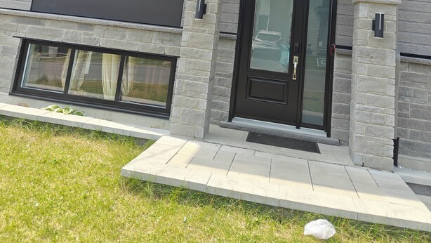 Una casa moderna de dos pisos con techo plano, ventanas amplias y fachada de piedra.
