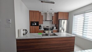 Una cocina moderna con armarios de madera, electrodomésticos de acero inoxidable y encimera de mármol.