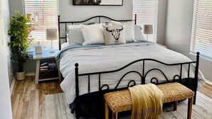 Ein Schlafzimmer mit einem Bett, einem Deckenventilator, einem Wandbild und einem Fenster mit Jalousien.