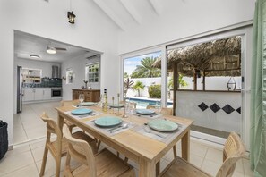 Una cocina moderna con comedor, vista a una piscina y una estructura de techo de paja.