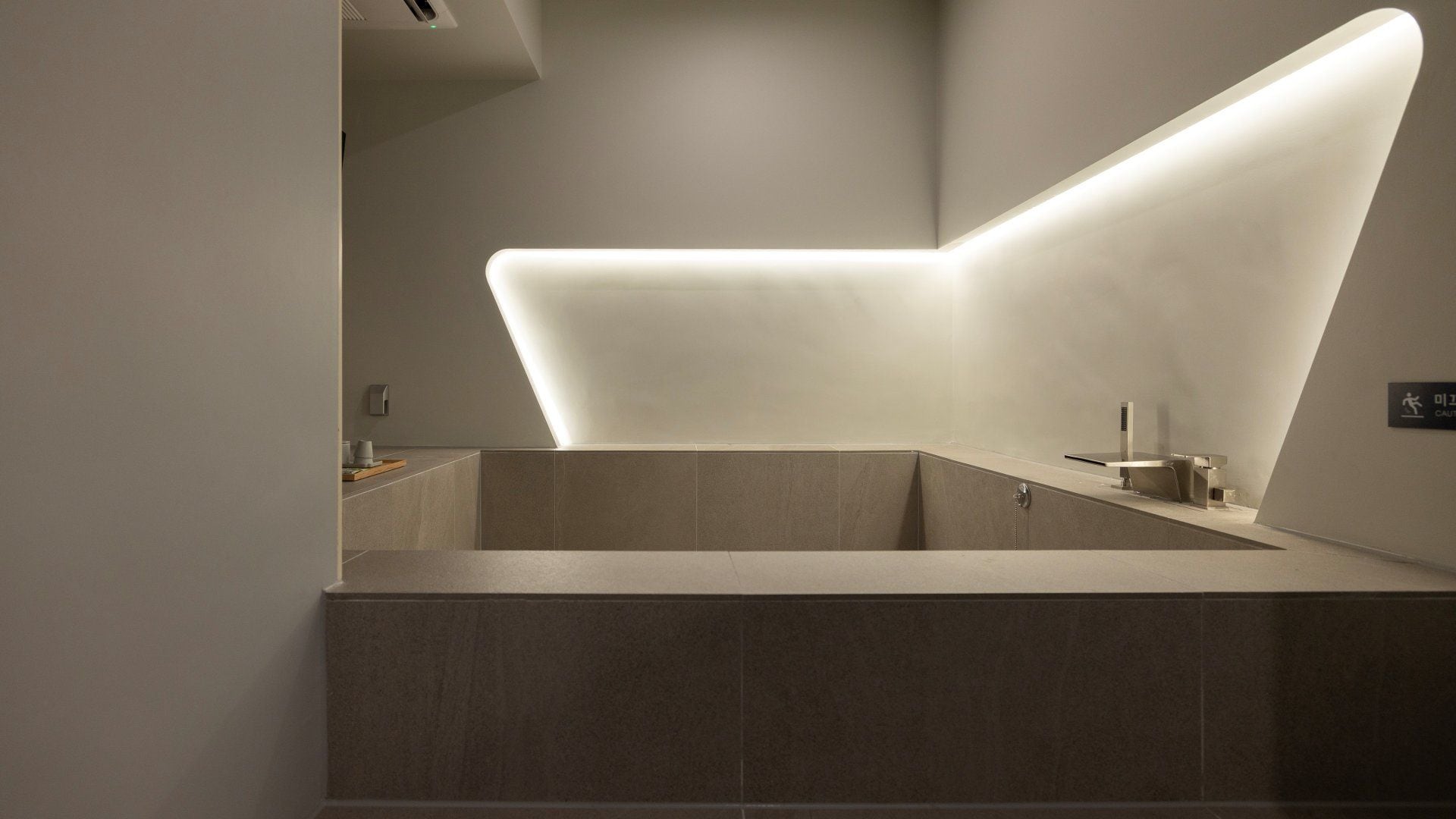Un baño moderno con una lámpara de diseño geométrico, un lavamanos empotrado y un perchero para toallas.