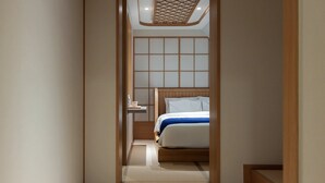 Un corridoio stretto che conduce a una camera da letto con una testiera di legno e un comodino.