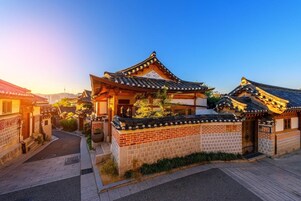 Una casa tradicional coreana con techo de tejas, paredes de ladrillo y un pequeño jardín.