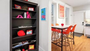A modern kitchen with white cabinets, a black countertop, and a red chair. - Chicago Citrus Charm 2BR  WestTown (Chicago)