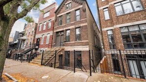 A row of three-story brick townhouses with external staircases and black railings. - Chicago Citrus Charm 2BR  WestTown (Chicago)