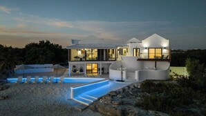 A modern two-story house with a swimming pool, outdoor seating, and a view of a mountain. - Opaline Villa -3BR 2bath Oceanfront (Providenciales)