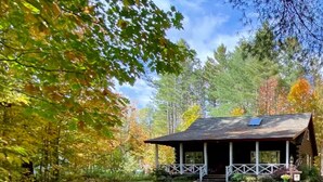A cabin with a porch, surrounded by trees and a grassy area. - Entire cabin in Speculator, New York (Speculator)