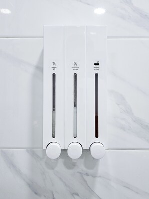 Dispensador de pared con tres compartimentos para champú, acondicionador y gel de baño.