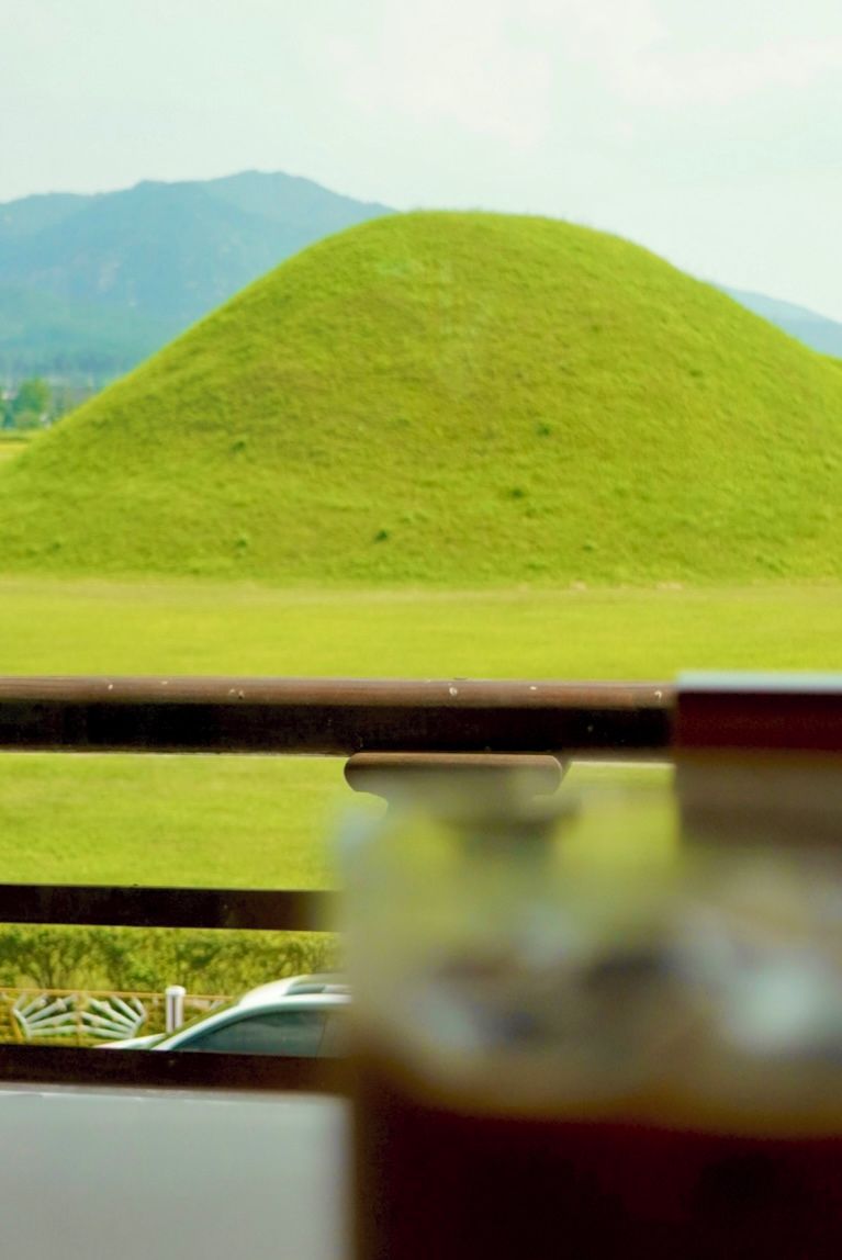 A view of a green hill with a metal railing in the foreground.