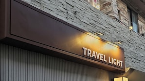 Ein Gebäude mit einem Schild, auf dem "TRAVEL LIGHT" und ein weiteres Schild für "TRAVEL HOSTEL" stehen.