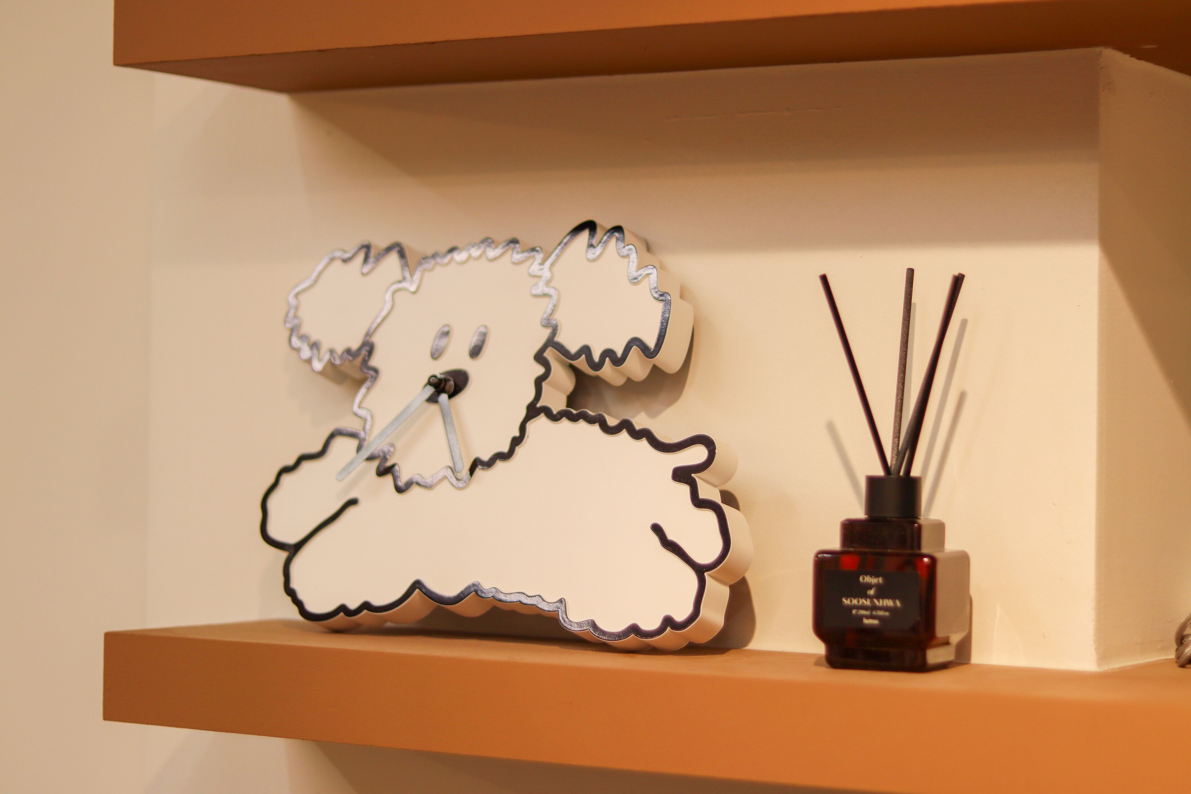 Una estantería con un objeto decorativo con forma de oso y un difusor de cañas.