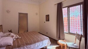 A bedroom with a bed, a chair, a window with curtains, and a door. - 3A retreat (Sti Fadma)