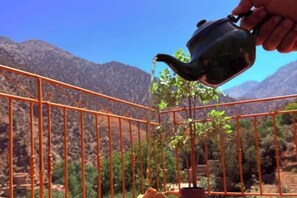 A hand pouring water from a teapot into a birdcage with a view of mountains in the background. - 3A retreat (Sti Fadma)