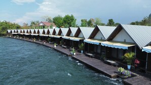 Reihenweise Bungalows mit Blick auf das Wasser, einer Holzterrasse und Sitzgelegenheiten im Freien.