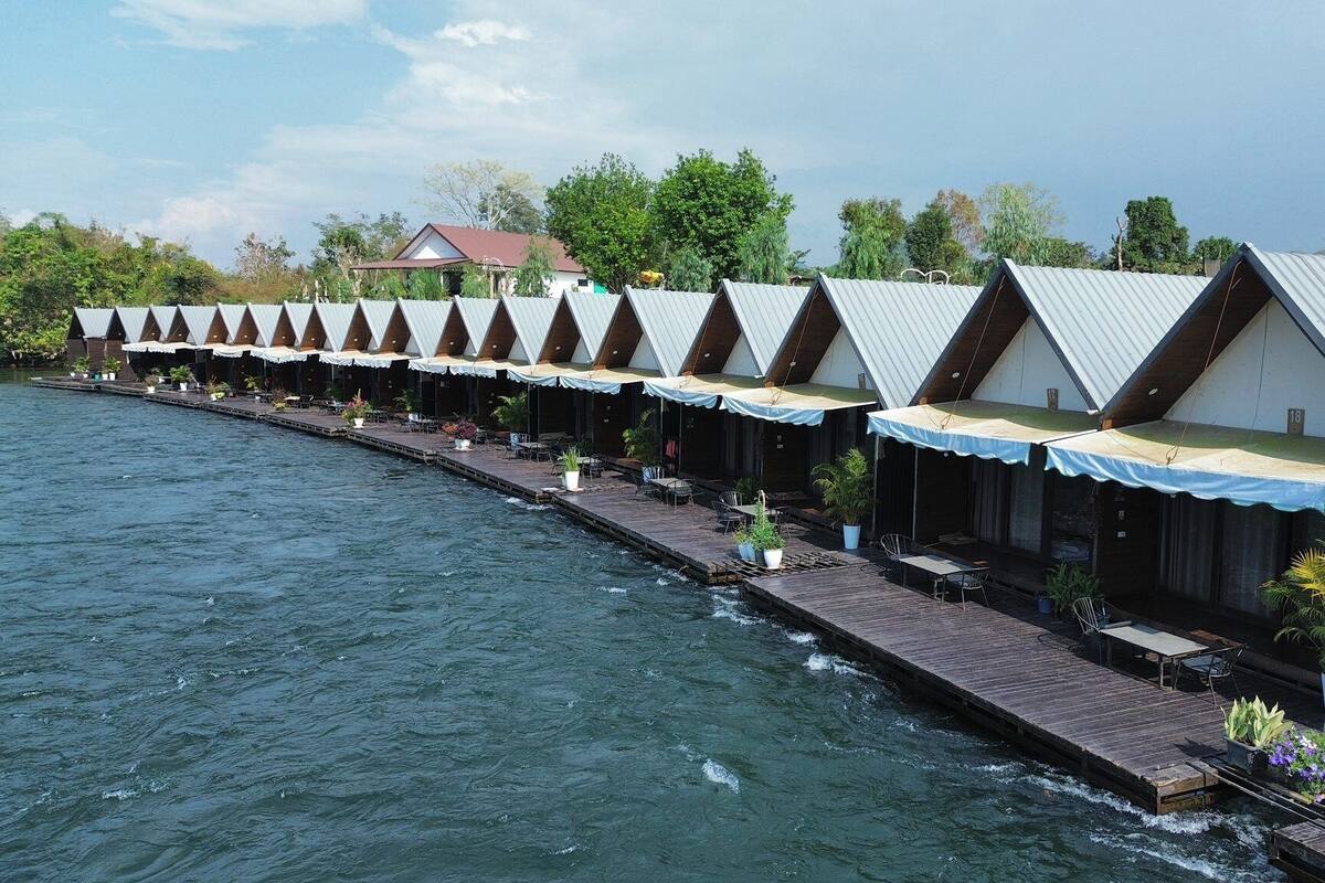 Reihenweise Bungalows mit Blick auf das Wasser, einer Holzterrasse und Sitzgelegenheiten im Freien.