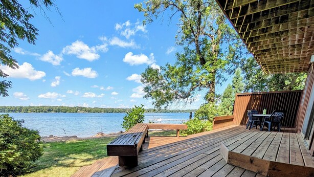 Une terrasse en bois avec un banc et une table, donnant sur un lac.